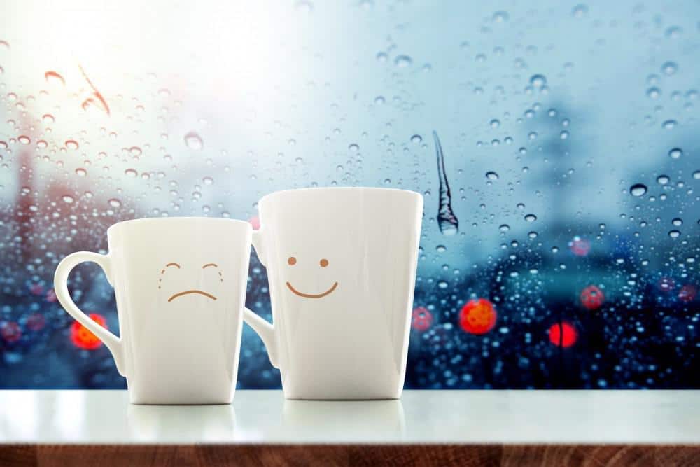 Two coffee cups with drawn on faces - one kind and one crying