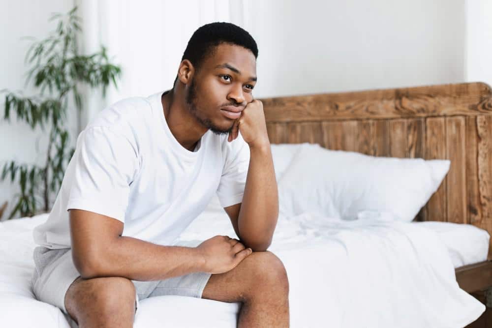 Man sits on bed contemplating stress